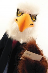 Auggie Eagle wearing a suit jacket holding a business card