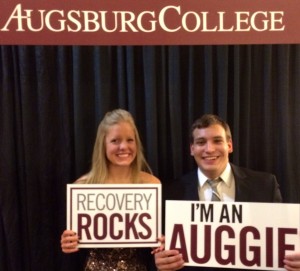 Two students holding signs reading "Recovery Rocks" and "I'm an Auggie".