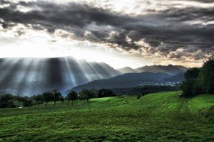 Sun shining through clouds on a mountain.
