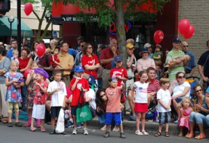 Children and adults, roadside, wearing red, white, and blue.